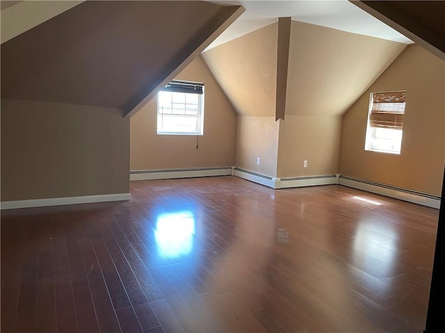 additional living space with a baseboard heating unit, baseboards, vaulted ceiling, and wood finished floors