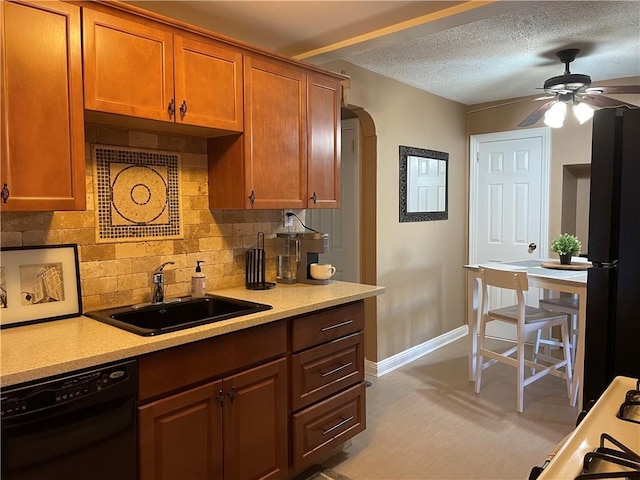 kitchen featuring arched walkways, light countertops, a sink, ceiling fan, and black appliances