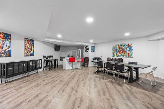 dining space featuring baseboards, light wood finished floors, and recessed lighting