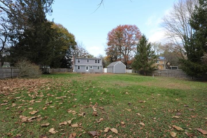 view of yard with a fenced backyard, an outdoor structure, and a storage unit