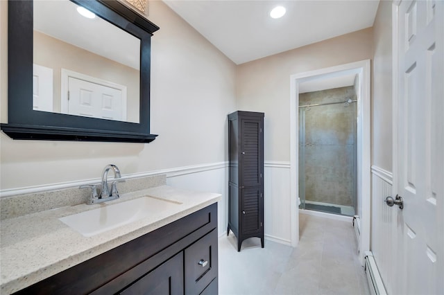 full bathroom with a stall shower, a wainscoted wall, vanity, and a baseboard radiator