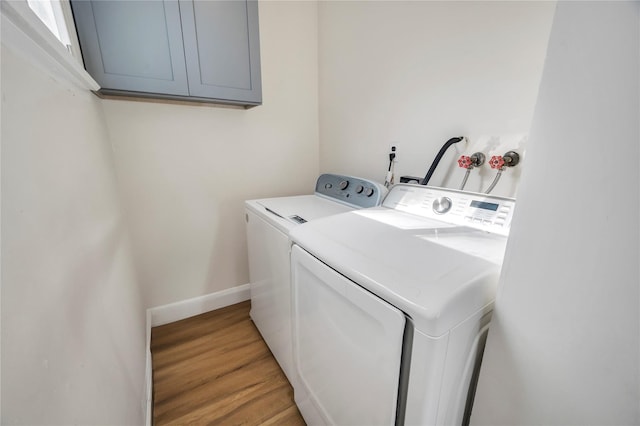 laundry area with baseboards, washer and clothes dryer, cabinet space, and light wood-style floors