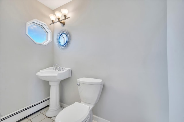 half bathroom with a baseboard heating unit, tile patterned flooring, baseboards, and toilet