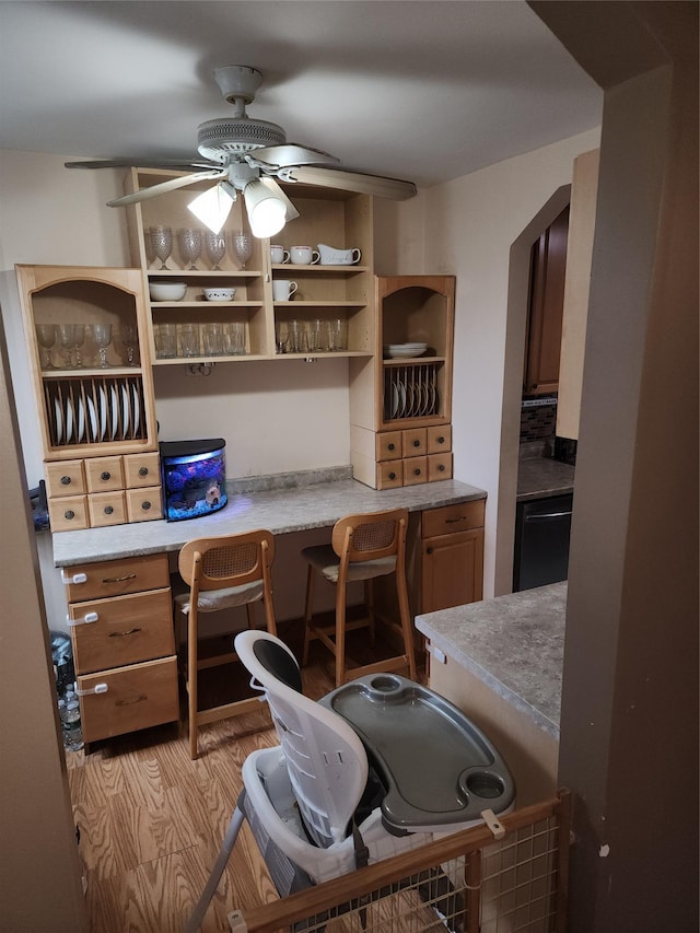 office with built in study area, ceiling fan, and light wood finished floors