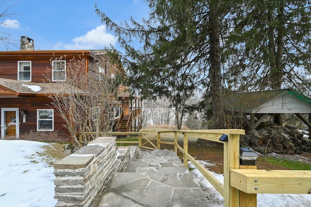 exterior space with stairway, a shingled roof, and a chimney