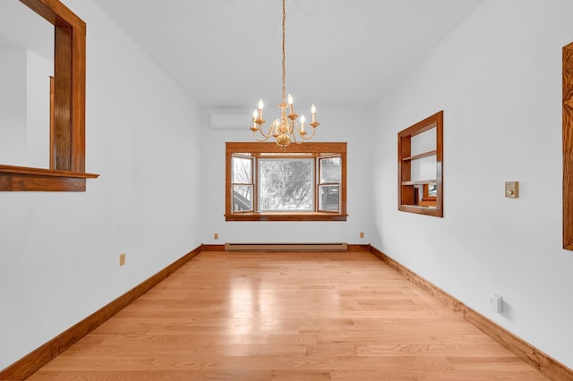 spare room featuring a notable chandelier, light wood-style flooring, baseboard heating, a wall mounted air conditioner, and baseboards