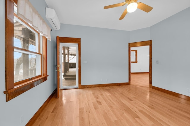 spare room featuring light wood-style floors, a ceiling fan, baseboards, and a wall mounted AC