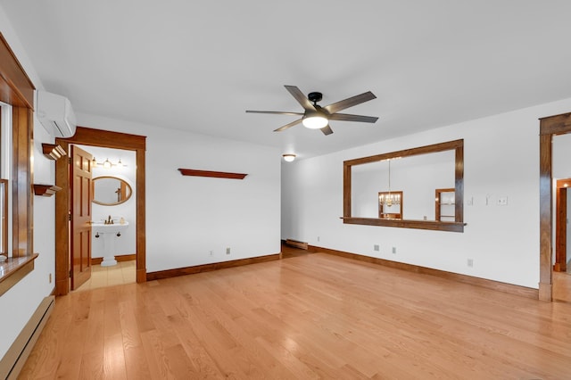 spare room with a baseboard heating unit, light wood-style floors, a wall mounted air conditioner, baseboards, and ceiling fan with notable chandelier