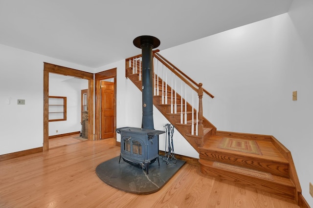 stairs with a wood stove, baseboards, and wood finished floors