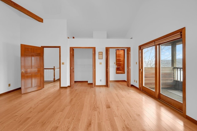 unfurnished bedroom with access to exterior, baseboards, high vaulted ceiling, and light wood-style floors