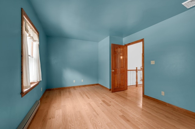 interior space with a baseboard heating unit, baseboards, visible vents, and light wood finished floors