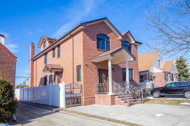 traditional-style home featuring brick siding and fence