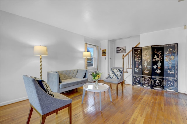 living area featuring wood-type flooring, stairs, and baseboards