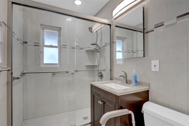 full bathroom with a stall shower, tile walls, toilet, and vanity