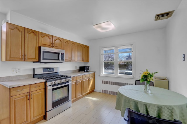 kitchen featuring light countertops, appliances with stainless steel finishes, radiator heating unit, and visible vents