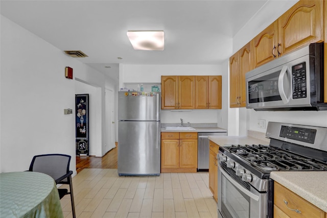 kitchen featuring visible vents, light wood-style flooring, appliances with stainless steel finishes, light countertops, and a sink