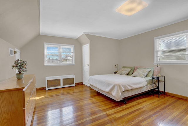 bedroom featuring light wood-style floors, baseboards, visible vents, and vaulted ceiling