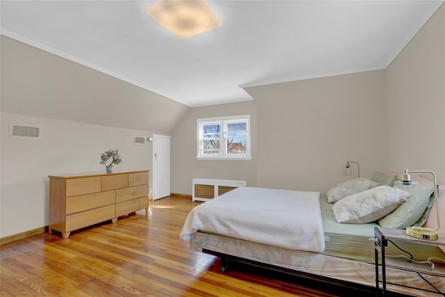 bedroom featuring baseboards, visible vents, vaulted ceiling, and light wood finished floors