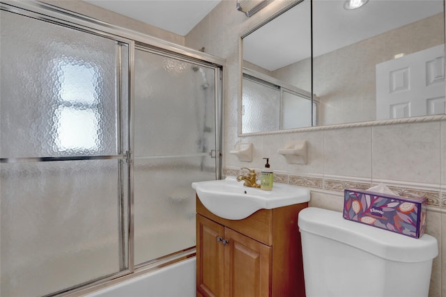 bathroom featuring tile walls, tasteful backsplash, toilet, combined bath / shower with glass door, and vanity