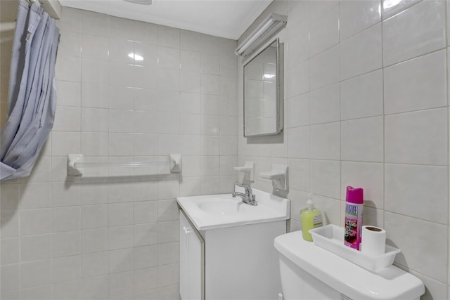 bathroom with toilet, tile walls, and vanity