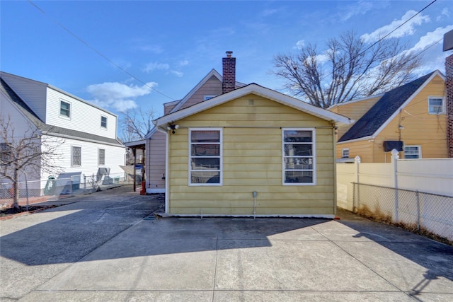 rear view of property featuring fence and a chimney