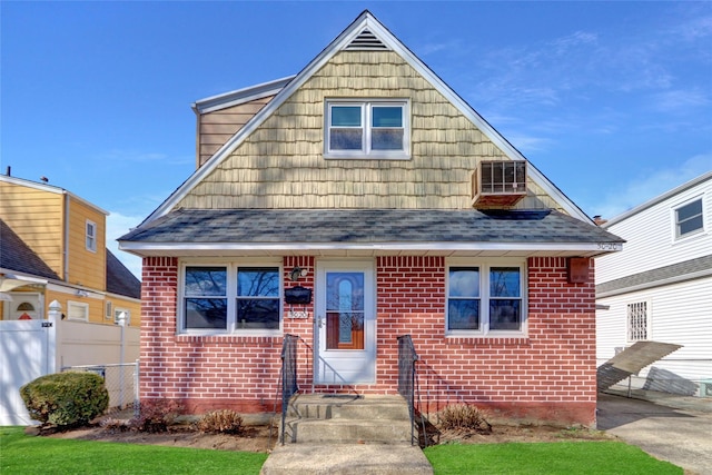 view of front of property with brick siding, a shingled roof, and fence