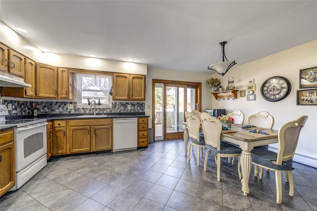 kitchen with dark countertops, white appliances, brown cabinetry, and a sink