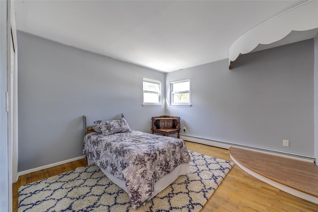 bedroom with baseboards, baseboard heating, and wood finished floors