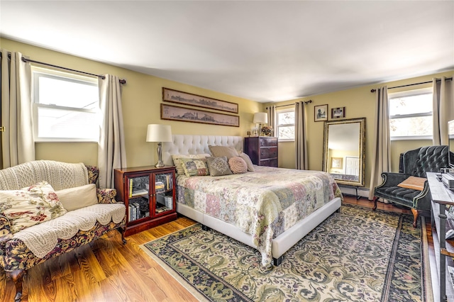 bedroom with multiple windows and wood finished floors