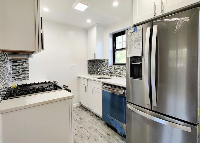 kitchen featuring decorative backsplash, white cabinetry, a sink, stainless steel fridge, and dishwashing machine