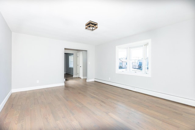 spare room featuring a baseboard radiator, wood finished floors, and baseboards