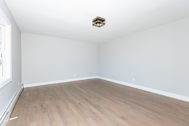 unfurnished room with baseboards, baseboard heating, and wood finished floors