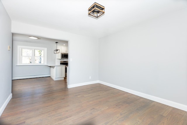 unfurnished living room featuring baseboards, baseboard heating, and wood finished floors