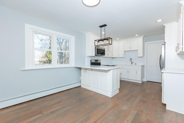 kitchen featuring white cabinets, appliances with stainless steel finishes, and baseboard heating