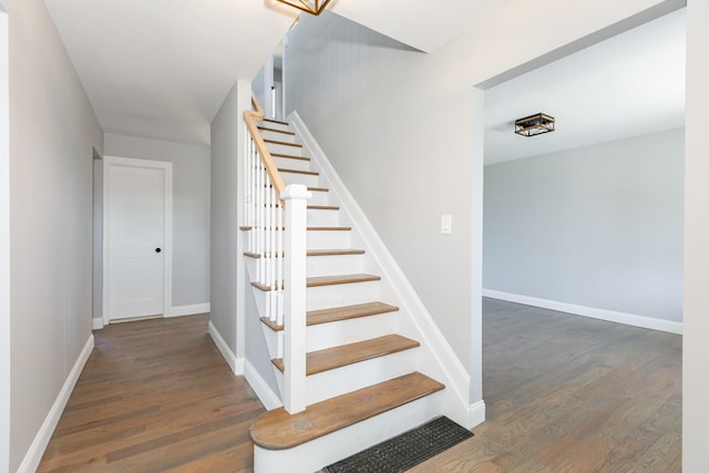 staircase with baseboards and wood finished floors