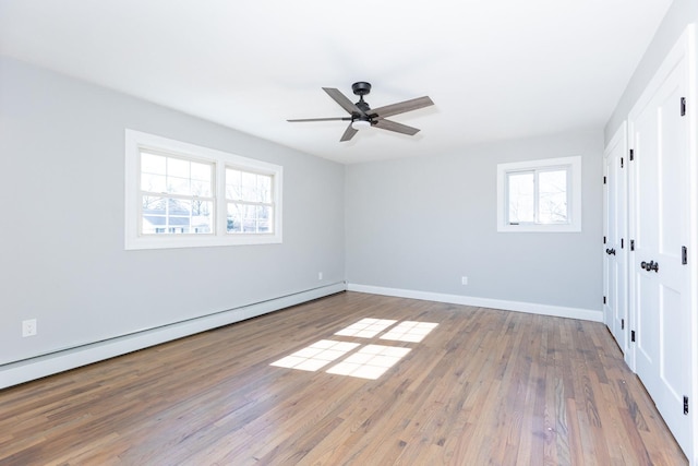 unfurnished bedroom featuring ceiling fan, a baseboard radiator, wood finished floors, and baseboards