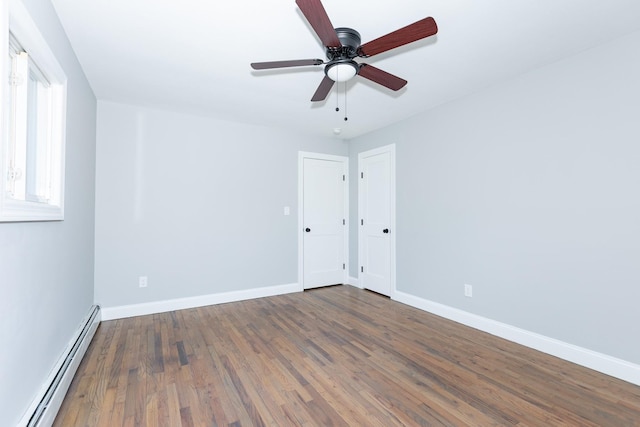 empty room with a baseboard heating unit, wood finished floors, a ceiling fan, and baseboards