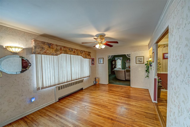 spare room featuring radiator, wallpapered walls, ornamental molding, and hardwood / wood-style floors