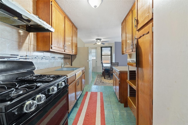 kitchen with range with gas cooktop, brown cabinets, a sink, and under cabinet range hood