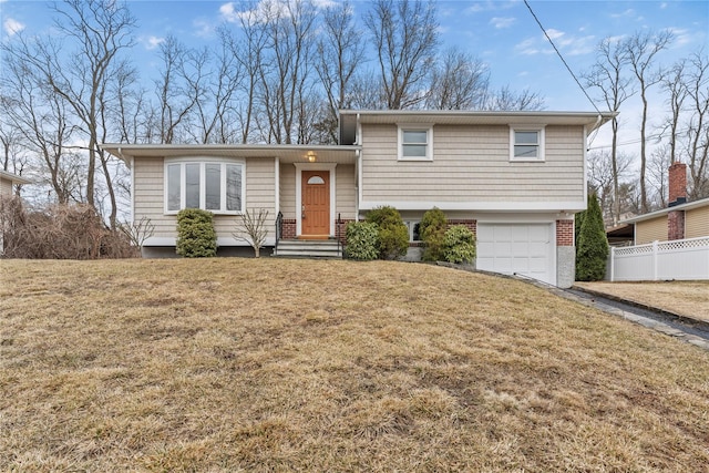 split level home with an attached garage, fence, a front lawn, and brick siding