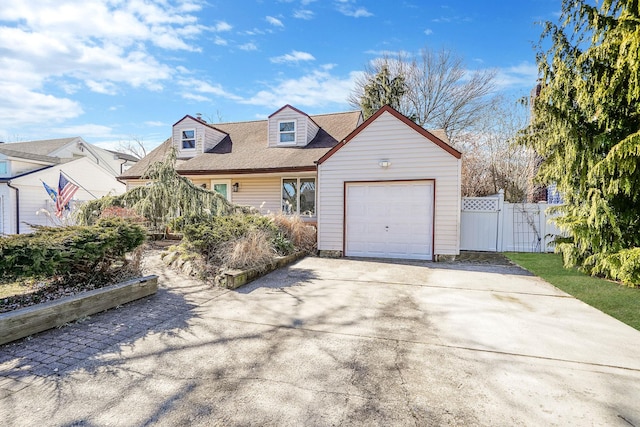 new england style home with a garage, driveway, fence, and a gate