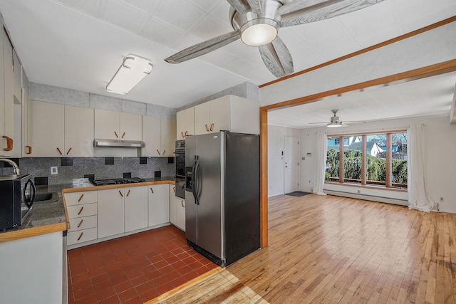 kitchen featuring black gas cooktop, a baseboard heating unit, a ceiling fan, refrigerator with ice dispenser, and under cabinet range hood