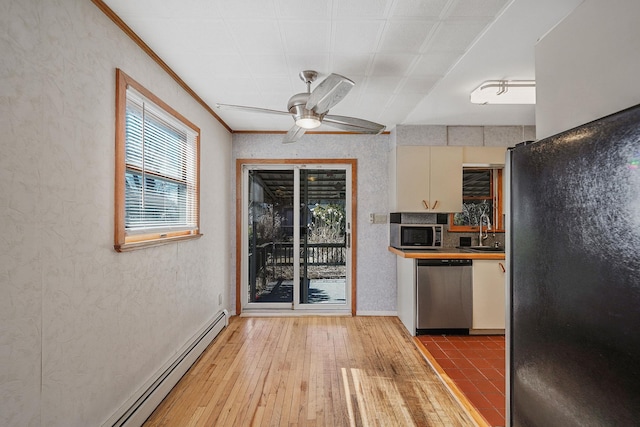 kitchen with ceiling fan, a baseboard heating unit, stainless steel appliances, a sink, and light wood-type flooring