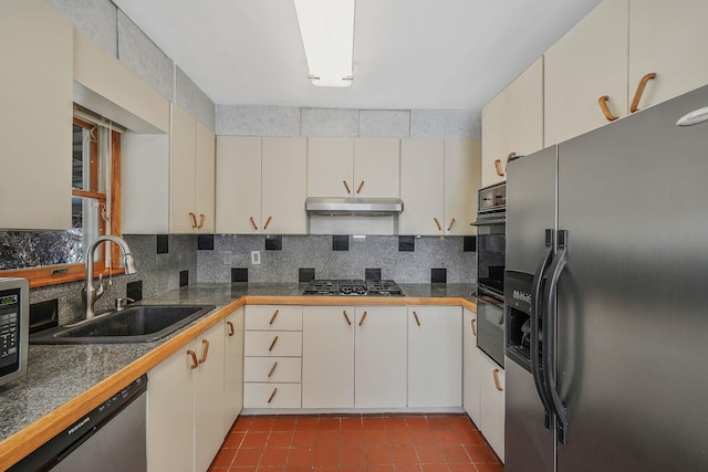 kitchen with tile counters, tasteful backsplash, a sink, under cabinet range hood, and black appliances