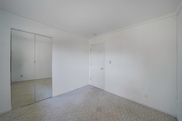 unfurnished bedroom with carpet, crown molding, baseboards, and a closet