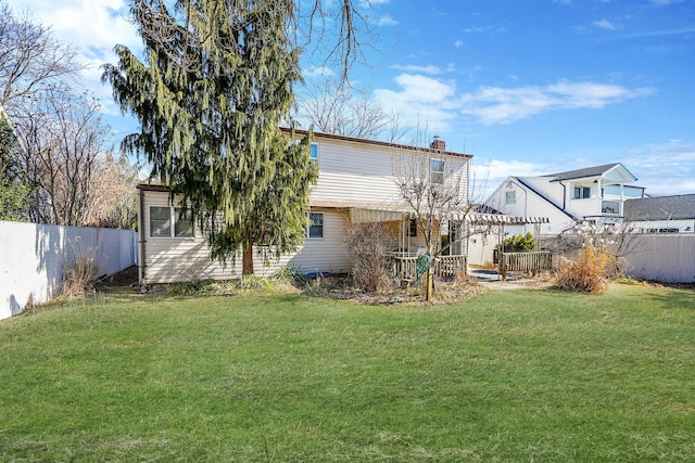 back of house with a lawn, a chimney, and fence