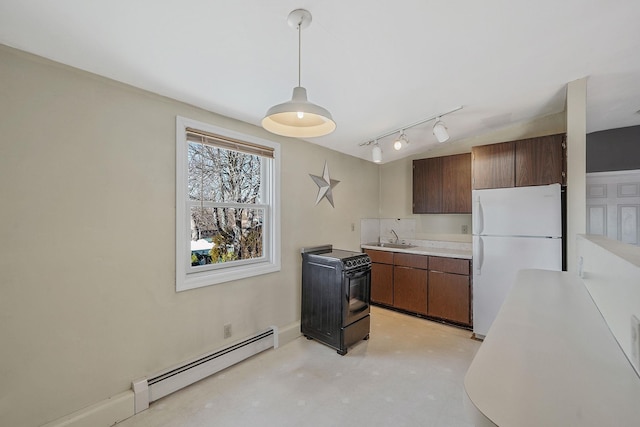 kitchen with light countertops, a baseboard heating unit, freestanding refrigerator, a sink, and concrete floors