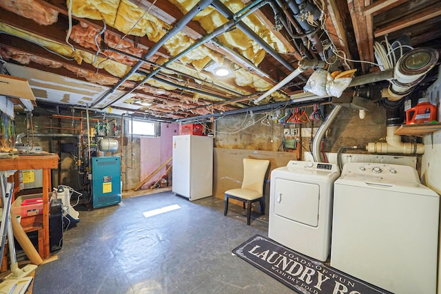 below grade area featuring a heating unit, washing machine and dryer, and freestanding refrigerator