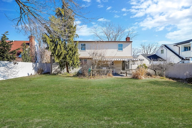 rear view of house featuring a fenced backyard, a lawn, and a chimney