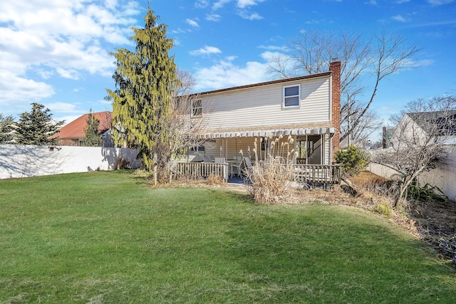 back of house with a chimney, fence, and a yard